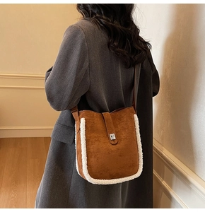Detail view of brown suede bucket bag with white faux shearling trim and metal buckle