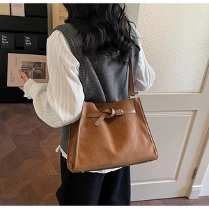 Brown suede tote bag side view on shoulder showing large capacity and buckle detail