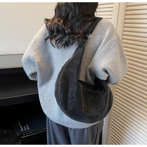 Dettaglio della borsa hobo nera con cuciture a contrasto bianche e ricamo con lettere