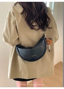 Détail du sac demi-lune noir rétro avec pendentif en peluche et logo doré chic