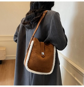 Detail of suede bucket bag with white fleece trim and elegant silver metal buckle