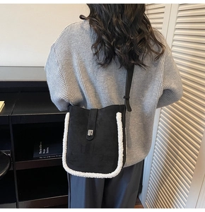 Detail view of black suede bucket bag with white fleece trim and metal buckle on model