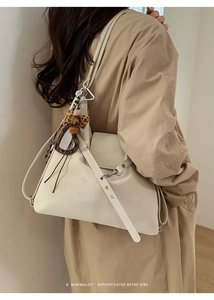 Détail d'un sac cabas en cuir beige avec un nœud léopard porté à l'épaule par un mannequin