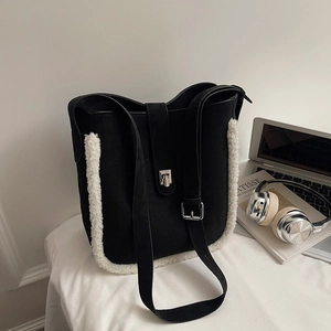 Close-up of black suede bucket bag with white faux fur trim and silver metal buckle
