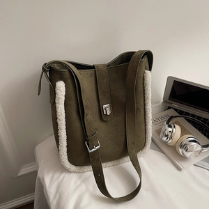 Detail of dark green suede bucket bag featuring white faux shearling trim and silver buckle