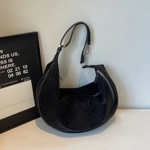 Dettaglio borsa hobo in camoscio nero con cuciture bianche e ricamo floreale