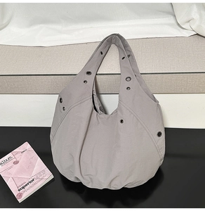 Close-up of grey hobo bag showing metal eyelet details and textured nylon fabric