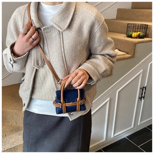 Detailansicht der Mikro-Jeanshandtasche mit braunem Lederbesatz und schmalem Schultergurt