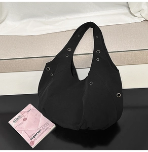 Detail of black canvas shoulder bag with silver metal eyelets and large capacity design