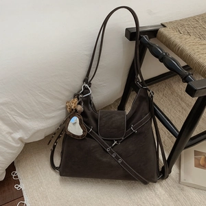 Détail d'un sac hobo marron vintage avec coutures contrastées et breloque léopard