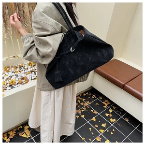 Close-up of black suede tote bag with silver ring decor in a seasonal autumn setting