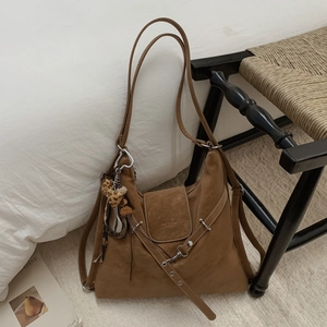 Détail d'un sac hobo marron vintage avec chaînes argentées, rivets et glands en cuir