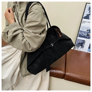 Detail of a large black suede tote bag with minimalist metal D-ring for daily commuting
