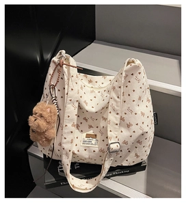 Close-up of retro white corduroy tote bag with heart patterns and plush puppy charm