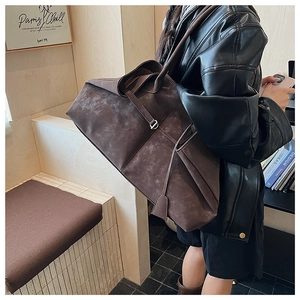 Close-up of large brown suede tote bag with slim shoulder straps and buckle closure