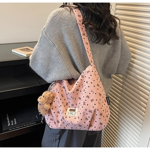 Pink corduroy tote bag with heart and bow patterns worn on shoulder with bear charm
