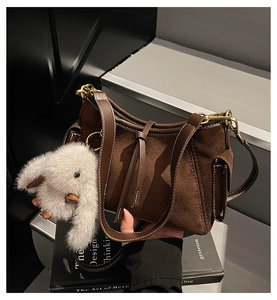 Detailed view of brown suede baguette bag with contrast stitching and rabbit plush charm