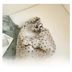 Detail of plush beige shoulder bag with blue floral pattern and large 3D bow decoration