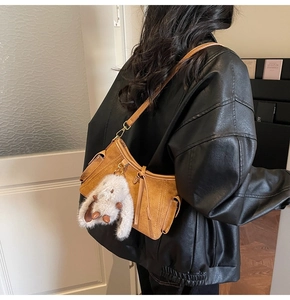 Detail view of a vintage brown crossbody bag with side pockets and cute rabbit pendant