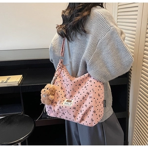 Detail of pink corduroy tote bag with heart bow pattern and brown plush bear charm