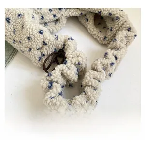 Close-up of plush cream faux fur bag strap with blue floral patterns and brown drawstring