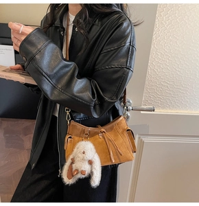 Detail view of retro caramel suede handbag with a cute white bunny plush keychain