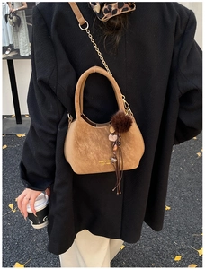 Vue détaillée du sac seau en daim marron orné d'un pompon en fourrure et de longues franges