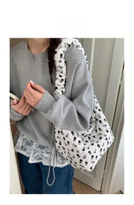 Detail of white tote bag with black polka dots and pleated bubble design shoulder strap