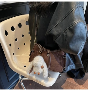 Close-up of retro brown suede crossbody bag featuring a cute white rabbit plush charm