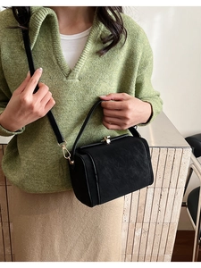 Vue détaillée d'un sac bandoulière noir structuré avec boucle en métal doré et poignée