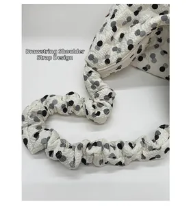 Detail of the drawstring strap design and textured polka dot fabric on the shoulder bag