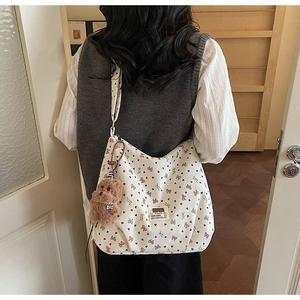 Detail of white corduroy tote bag with heart bow pattern and plush bear charm