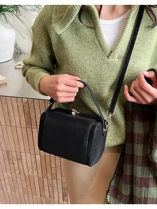 Détail du sac carré rétro noir avec fermoir doré rotatif et texture en cuir lisse