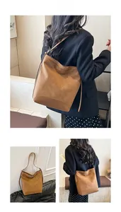 Detailed close-up of brown suede bucket bag with wide shoulder strap in caramel finish