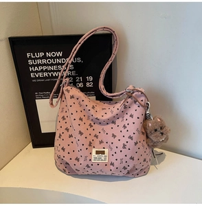 Detail view of pink corduroy tote bag with black bow patterns and a teddy charm