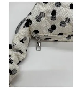 Macro view of smooth silver zipper detail on quilted polka dot textured tote bag
