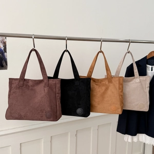 Minimalist vintage suede tote bags in four colors hanging on a metal rack