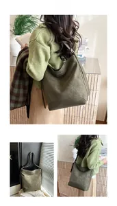 Detail of dark green suede hobo bag featuring wide straps and reinforced stitching