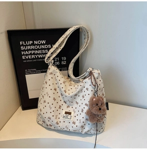Close-up of corduroy tote bag featuring bear prints and plush dog charm accessory