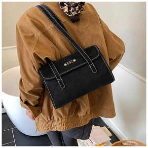 Detail of black matte shoulder bag with white contrast stitching and gold metal logo