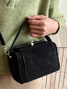 Sac docteur classique noir texturé avec finitions dorées porté par un mannequin chic