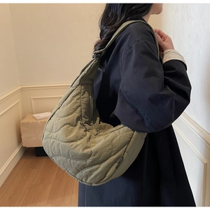 Detailed view of large olive green quilted nylon shoulder bag with wavy stitching