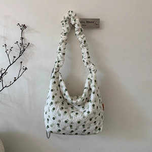 Detail of white bubble fabric shoulder bag with green polka dots and ruched strap design