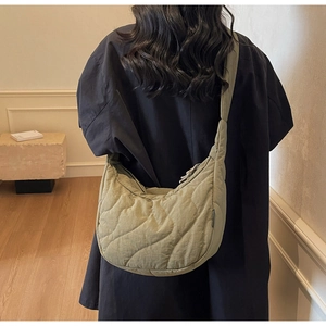 Quilted crescent crossbody bag in sage green shown as a lifestyle accessory on a model