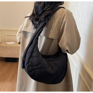 Close-up of black quilted crescent crossbody bag with adjustable wide shoulder strap