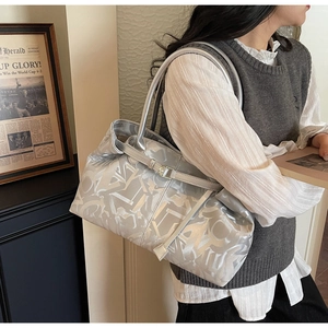 Detail of a large silver metallic tote bag with stylish buckle strap and long shoulder handles