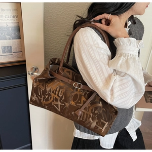 Detail of vintage brown tote bag with abstract lettering and sleek metal buckle strap