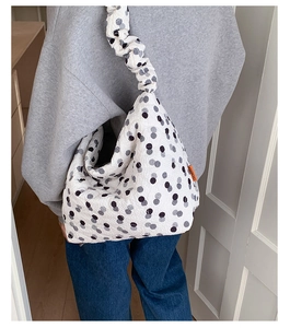 Close-up of quilted polka dot tote bag featuring ruched shoulder straps and side label