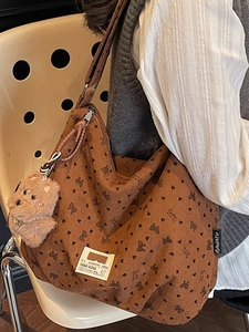 Brown corduroy tote bag with black bow patterns and a cute plush bear pendant accessory