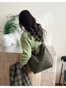 Detail view of large dark green suede hobo bag with side buckles and shoulder strap